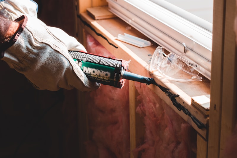 Carpenter nailing wood framing with insulation before drywall